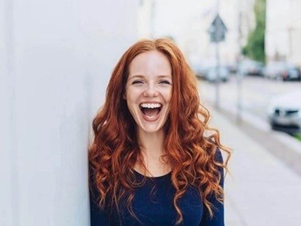 A woman with red hair is laughing