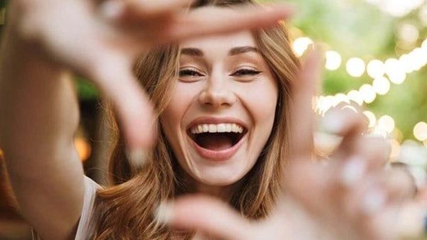 A woman smiling and making a hand gesture.