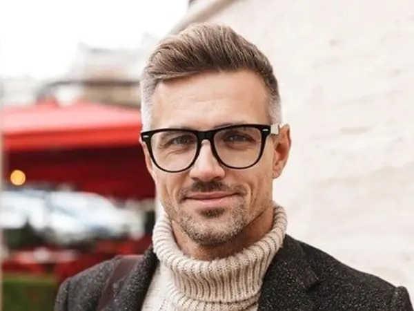 A man with glasses and a beard wearing a sweater