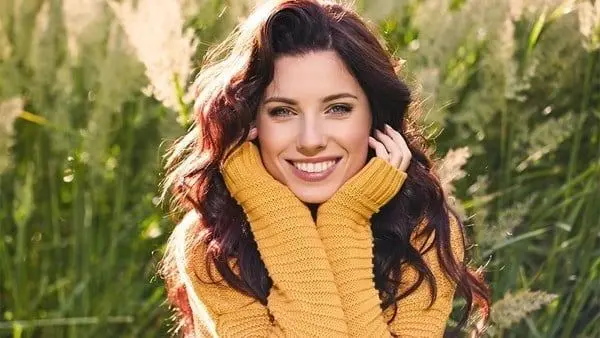 A woman in a yellow sweater smiling for the camera.