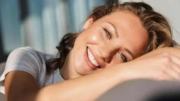 A woman smiling with her hand on the pillow.