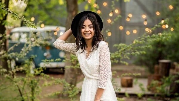 A woman in white dress and black hat.