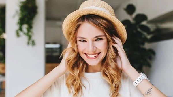 A woman with long hair wearing a hat.