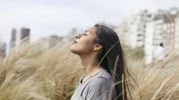 A woman with her eyes closed in the grass.