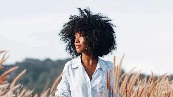 A woman with a big black afro in the grass.