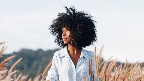 A woman with a big black afro in the grass.