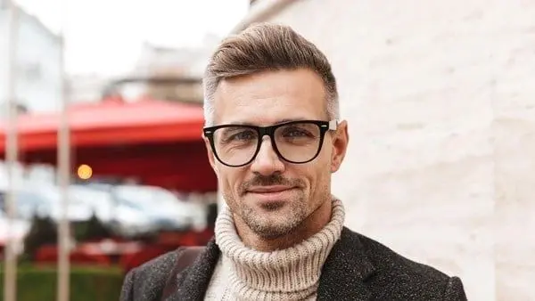 A man with glasses and a beard wearing a sweater.